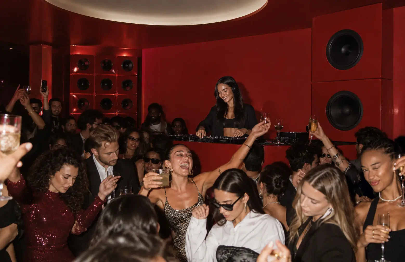 A DJ set at ARCHE at night with the crowd dancing in front of the red speaker wall