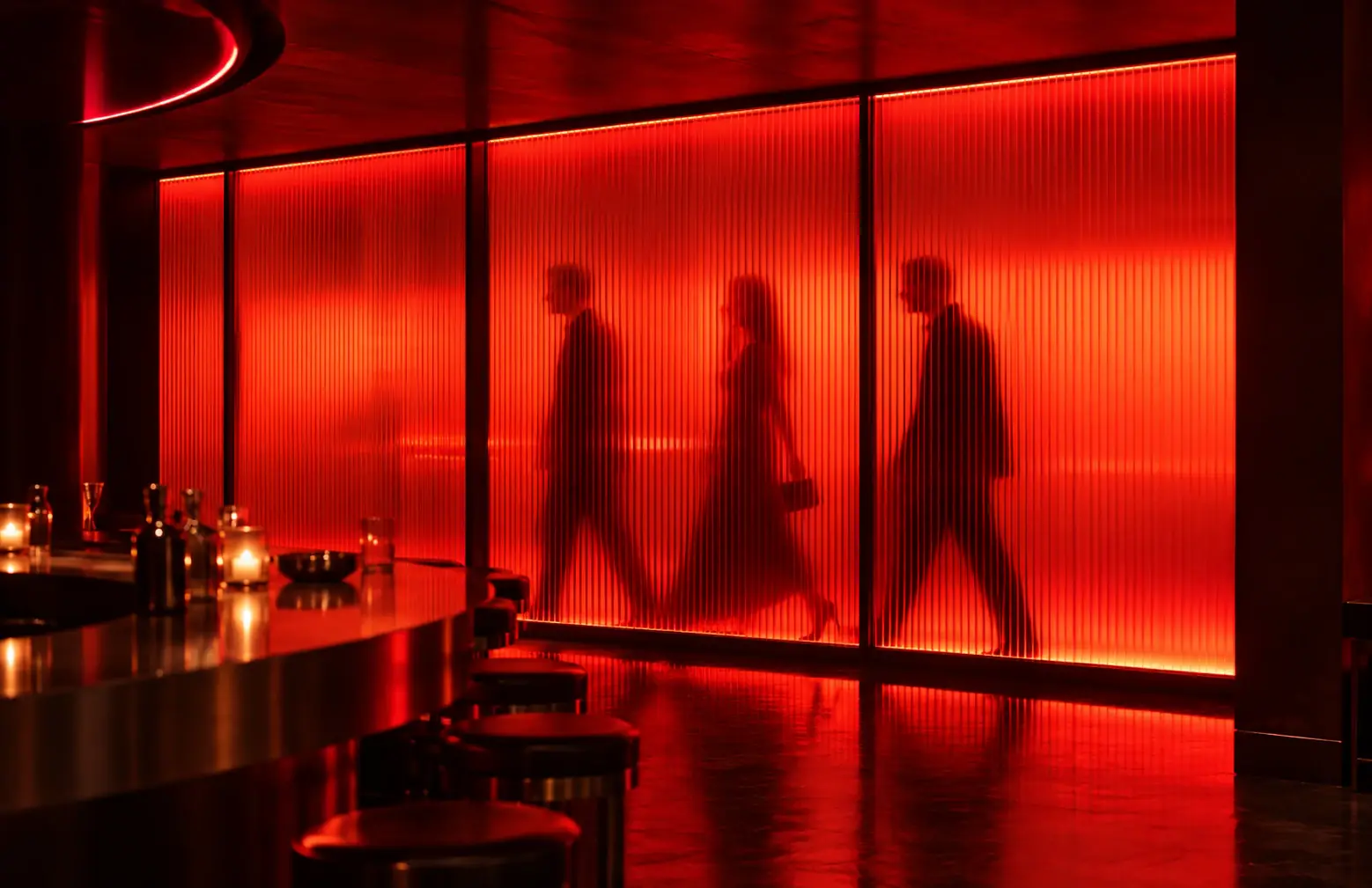 Silhouettes of guests passing behind backlit red fluted glass beside the ARCHE bar
