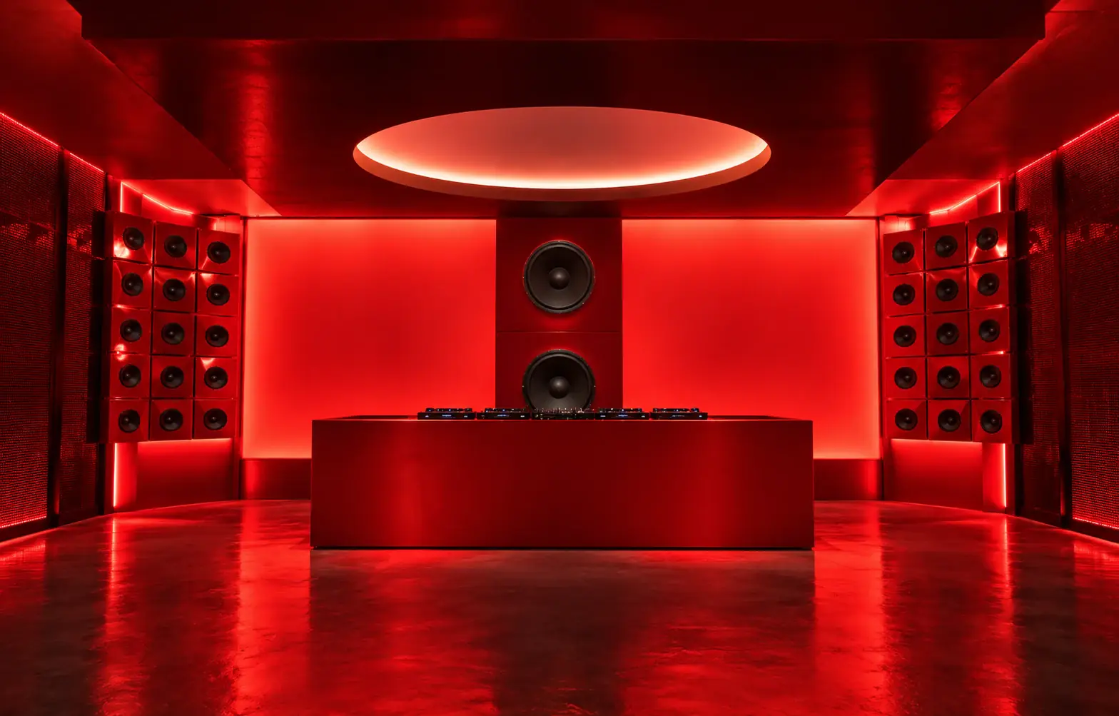 ARCHE DJ booth framed by stacked speakers in a monochrome red room under a circular light cove